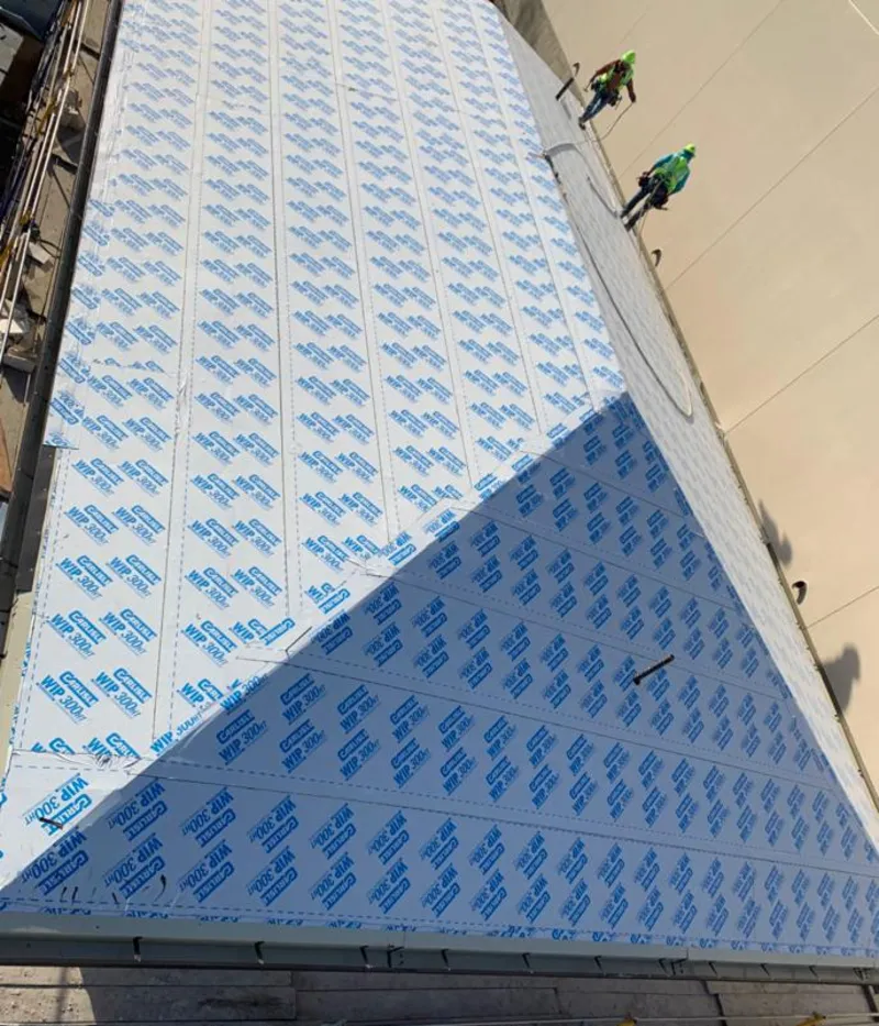 Professional roofers installing underlayment on a metal roof in Grand Haven